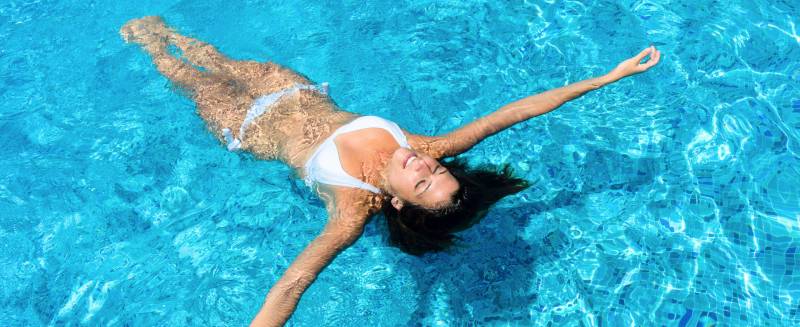 Femme dans piscine qui fait la planche