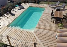 Piscine coque Manhattan 6 m parfaitement intégrée dans un jardin à Cuers.